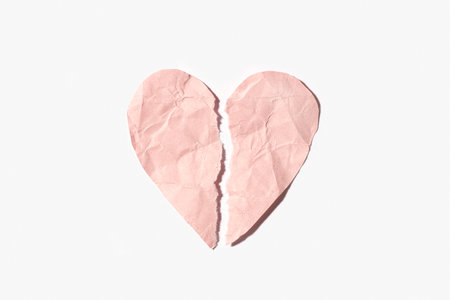 Broken heart made of pink crumpled paper isolated on white backgroundの写真素材