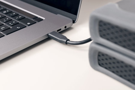 Detail of External hard disk cable connected to a modern laptop computer on desk
