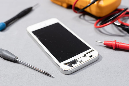 Close up of Smartphone with broken screen on electronic store workbench. Repairing damaged mobile...