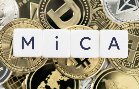 MiCA or Markets in Crypto Assets concept. Text on cube blocks on crypto coins background. Top view