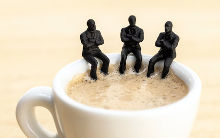 Group of businessman figurines sitting at a coffee cup talking to each other. Team working, brainstorming conceptの写真素材