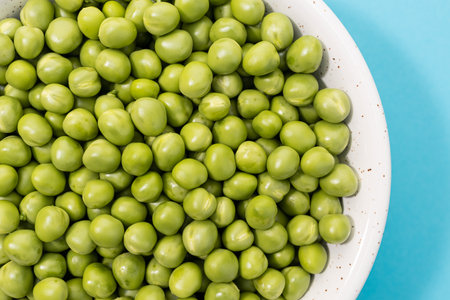 Close up of Fresh green peas in bowl on blue backgroundの写真素材