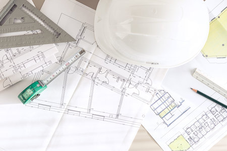 Architecture plans and contractor supplies on desk. Top view