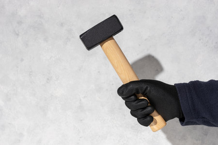 Construction worker holding a mason's hammer isolated on white textured wall with copy spaceの写真素材