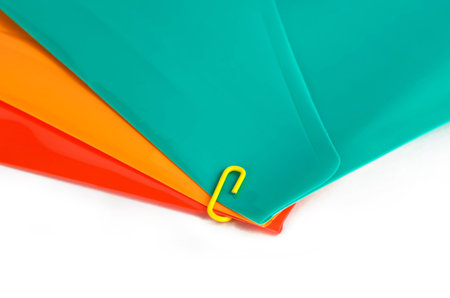 Three colored stationery folders and clip on a white background