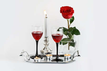 Red rose, wine and candles on a light backgroundの写真素材