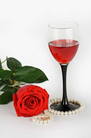 Roses, pearls and glass of red wine on a light backgroundの写真素材