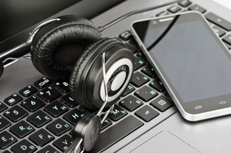 Black headphones and a smartphone close-up on the laptop keyboard