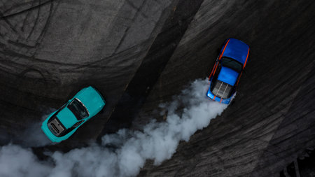 Aerial top view two cars drifting battle on asphalt race track with lots of smoke from burning tires, Two race cars competition drift battle view from above.の写真素材