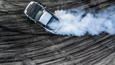 Aerial top view car drifting diffusion race drift car with lots of smoke from burning tires on speed track, Professional driver drifting car with lots of white smoke .の写真素材