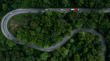 Aerial view car drive in green tree forest road winding road through the forest, Car drive on asphalt road between green tree forest, Electric vehicle EV car drive on asphalt road green tree forest.の写真素材