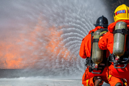 Fireman firefighter on duty fire fighting, Fireman firefighter spraying high pressure water, Fireman firefighter in fire fighting equipment uniform spray water from hose for fire fighting.の写真素材