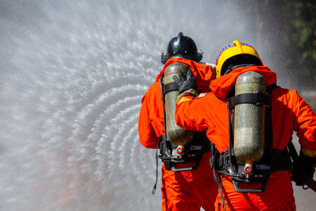 Fireman firefighter on duty fire fighting, Fireman firefighter spraying high pressure water, Fireman firefighter in fire fighting equipment uniform spray water from hose for fire fighting.の写真素材