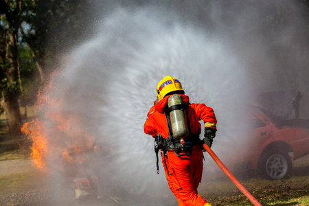 Fireman firefighter on duty fire fighting, Fireman firefighter spraying high pressure water, Fireman...