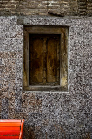 a texture wall with wooden closed window and orange benchの写真素材