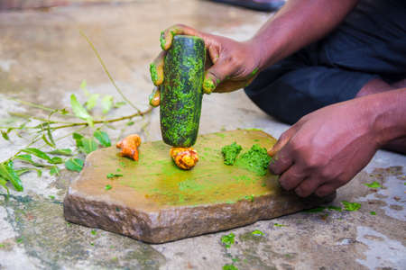 a medicine man grinding neem leaves and turmeric for making medicineの写真素材