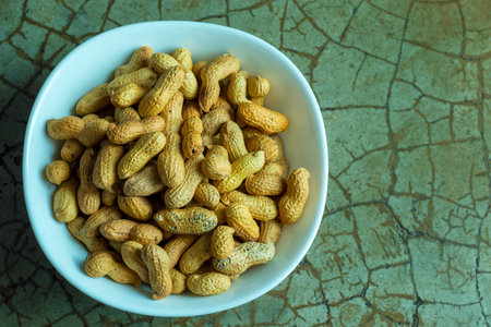 Peanuts in bowl on green background. Peanut in shell.