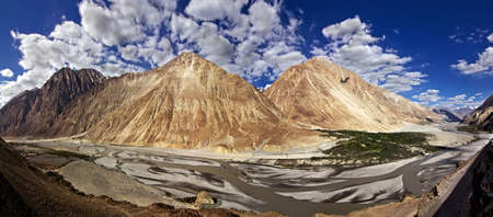 A panoramic view of Nubra Valley, yellow colored mountains and small village at the base of mountains; Ladakh, Jammu and Kashmir, Indiaの写真素材