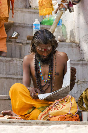 Varanasi, Uttarpradesh, India, April 1 2011:an Indian Sadhu reading a local news paper to keep up with morden timesのeditorial素材