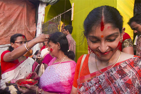KOLKATA - OCTOBER 10: A Women devotee smiles after appling sindhoor or to anotherのeditorial素材