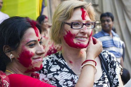 CALCUTTA - OCTOBER 6: A foreign tourist gets a warm cultural greeting with vermilion at Sindur Khela traditional ceremony on the final day of Durga Puja festival on October 6, 2011 in Calcutta, Indiaのeditorial素材
