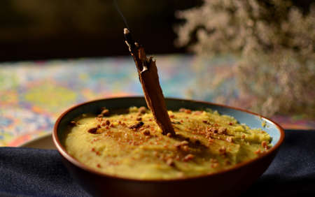 Dessert with cinnamon stick served in clay pot on a blue tablecloth.の写真素材