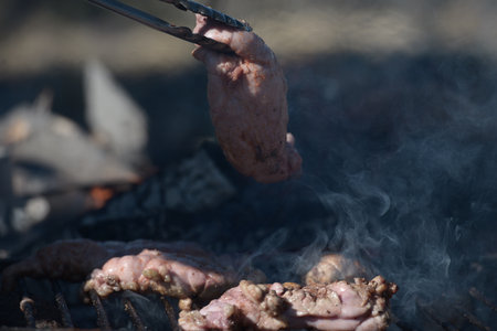 Metal clamp grabbing chinchulines and molleja, cooked on the coals in a grill.の写真素材