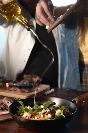 Man and woman cooking with olive oil on a table.