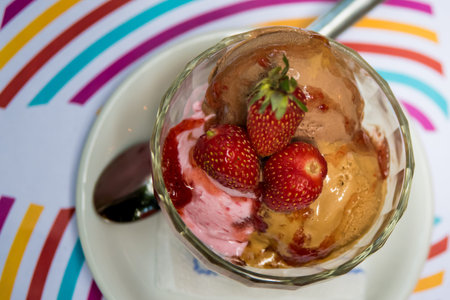 glass of ice cream with strawberries on a plate on a wooden table