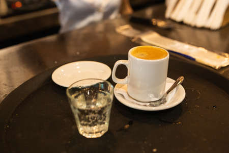 coffee with milk next to a glass of sparkling waterの写真素材