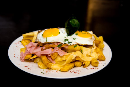 Fries with fried egg on a plate on a wooden table