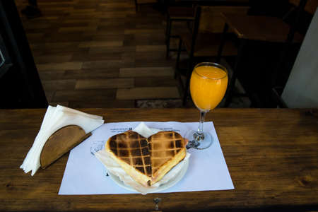 orange juice in a glass next to a ham and cheese waffleの写真素材