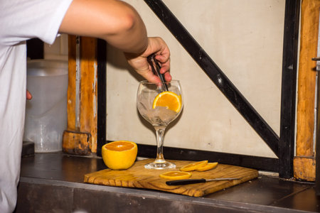 person placing orange slices in a glass