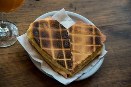 orange juice in a glass next to a ham and cheese waffleの写真素材