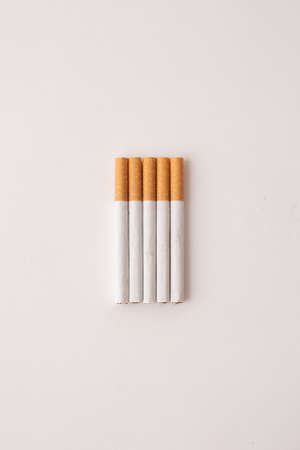 blonde cigarettes with filter on a white table, white backgroundの写真素材
