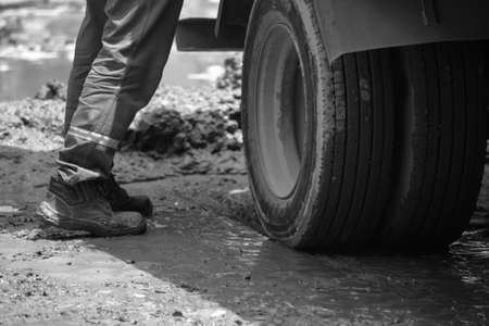 person standing on muddy asphalt next to a wheel of a vehicleの写真素材
