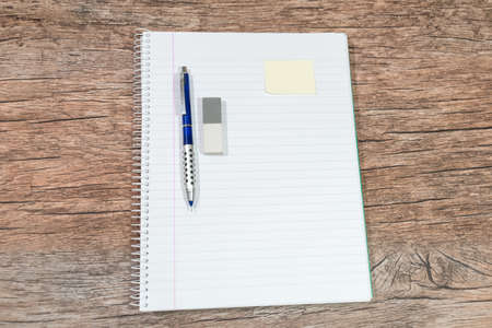 pen, pencil rubber on a notebook on a wooden tableの写真素材