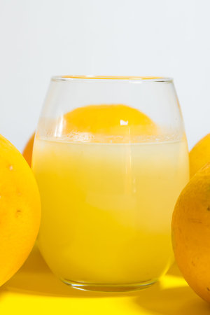 yellow grapefruits artistically placed on yellow table, glass of orange juice