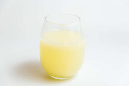 glass with yellow grapefruit juice on tableの写真素材