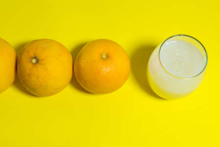 yellow grapefruit side by side on yellow table, glass of milkの写真素材