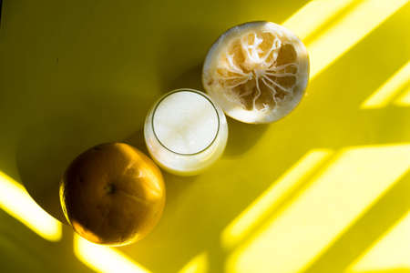 yellow grapefruits on yellow table with shade, glass of yellow grapefruit juiceの写真素材