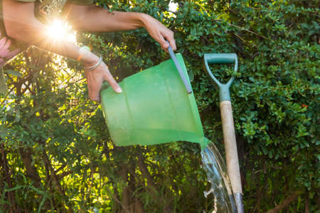 person washing a metal shovel with a bucket of waterの写真素材