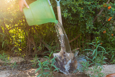 person washing a metal shovel with a bucket of water