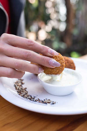 person dipping in sauce on a plate a croquetteの写真素材