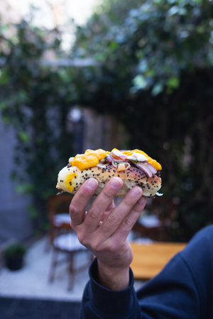 person with a hot dog in hand with different dressings