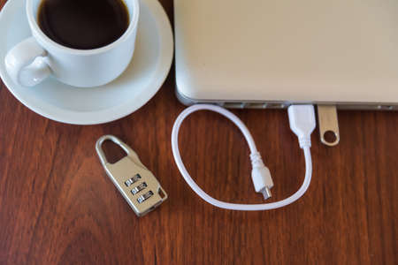 coffee cup and padlock next to a laptop with a pen drive plugged inの写真素材