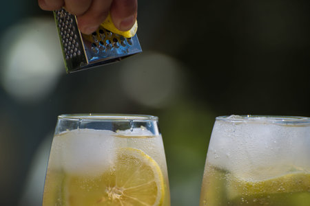 bartender grating lemon peel over lemon cocktails