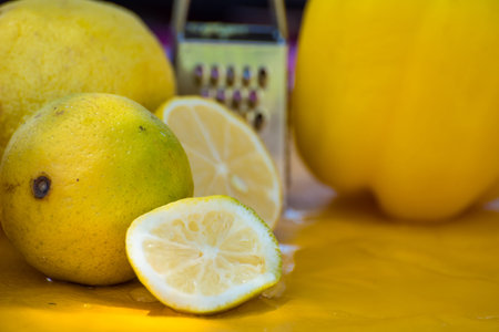 lemons cut and whole on a cutting board, grater next to it