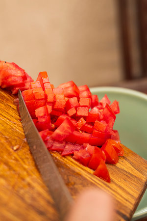 person placing diced tomatoes for cookingの写真素材