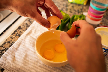 person breaking eggs on a ceramic containerの写真素材